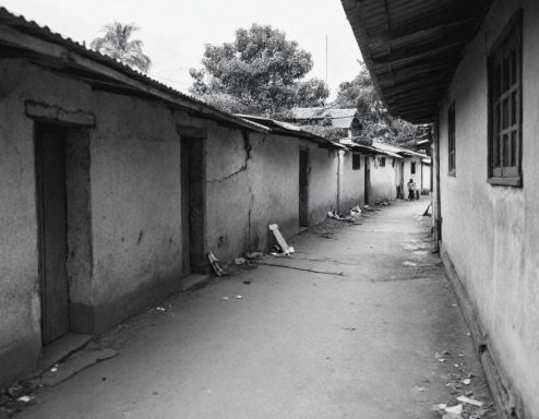 Vicolo stretto tra edifici di muratura, con porte in legno e spazzatura sparsa.
